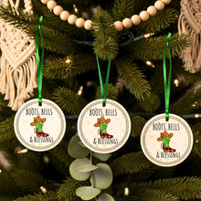 Three Christmas ornaments with 'Boots, Bells & Blessings' text and cowboy graphics on a decorated tree.