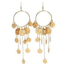 Gold hoop earrings with dangling gold coins and chains on a white background