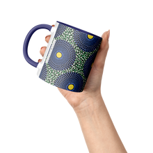 hand holding a blue yellow African pattern coffee mug