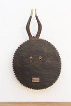 Decorative wall mask with antlers and a circular base on a white background