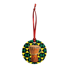 Decorative ornament with a drum design on a geometric patterned background, hanging from a red ribbon.