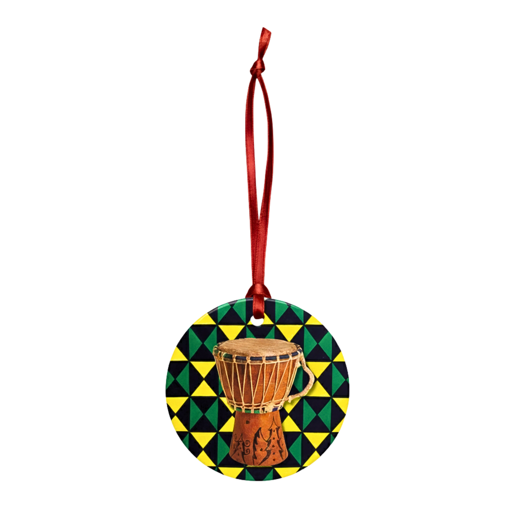 Decorative ornament with a drum design on a geometric patterned background, hanging from a red ribbon.