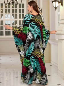 Woman wearing a colorful leaf-patterned dress in an elegant interior setting.