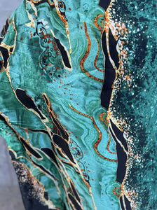 Close-up of a fabric with a marbled pattern in teal, black, and gold.
