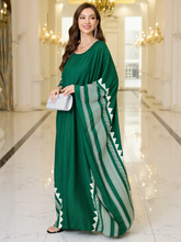 Woman wearing a green dress with white patterns in an indoor setting