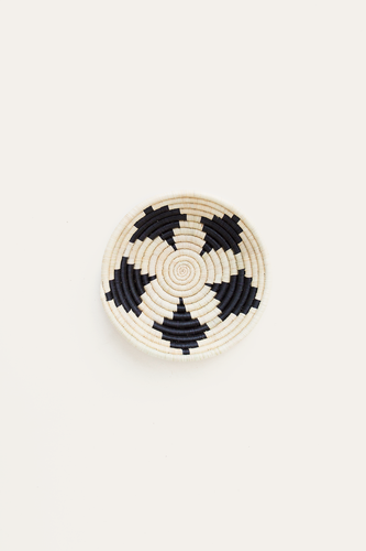 Round woven basket with black and white pattern on a beige background