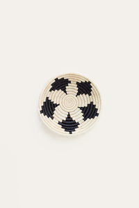 Round woven basket with black and white pattern on a beige background