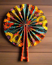 Colorful floral-patterned hand fan with wooden handle on a white background