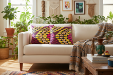 Living room with a beige sofa, colorful pillow, and plants