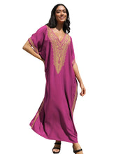 Woman wearing a magenta caftan with gold embroidery on a white background