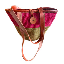 Woven handbag with pink top section, green middle section, and brown leather handle on a white background