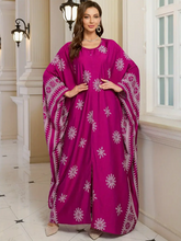 Woman wearing a vibrant pink dress with white patterns in an elegant interior setting.