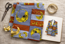 Colorful African fabric with scissors, measuring tape, and jacket sketch on a linen surface.