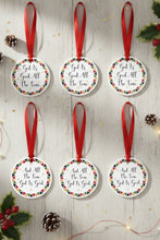 Set of six Christmas ornaments with red ribbons on a wooden surface with festive decorations.