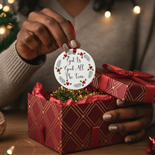 Person holding a religious Christmas ornament with decorative text over a gift box.