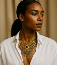 Woman wearing a white shirt and gold necklace against a beige background