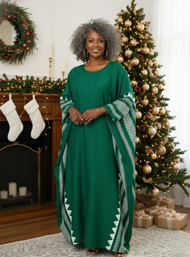 Woman in a green Kaftan standing in a festive room with Christmas decorations.