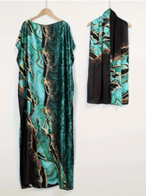 Teal and black patterned dress on a hanger against a white background