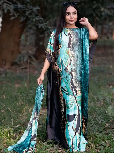 Woman wearing a long, patterned dress standing outdoors with trees in the background