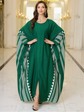 Woman wearing a green dress with white tribal patterns in an elegant indoor setting