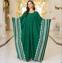 Woman wearing a green dress with white african patterns in an elegant interior setting