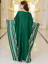 Woman wearing plus size green dress with white patterns in an elegant interior setting