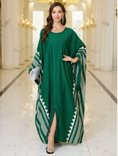 Woman wearing a green dress with patterned sleeves in an elegant interior setting