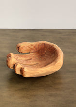 Wooden bowl shaped like a hand on a brown surface with a white background