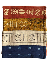 African mud cloth fabric textile with geometric patterns in red, yellow, and blue on a white background
