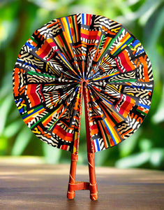 Colorful patterned fan with leather handle on a tropical background