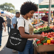 Woman shopping at an outdoor market with a 'I AM UBUNTU' tote bag.