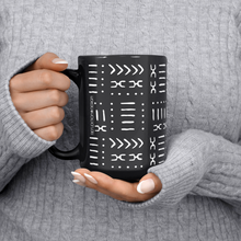 black white African pattern coffee mug held in hand by a woman wearing a sweater.