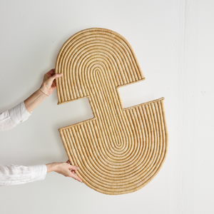 Person holding a unique shaped woven mat against a white wall