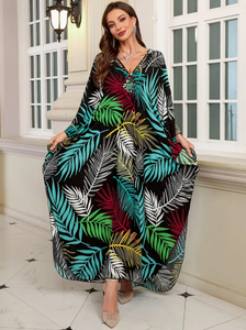 Woman wearing a colorful leaf-patterned dress indoors.