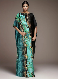 Woman wearing a long, patterned dress with a gradient of green, black, and gold on a neutral background.