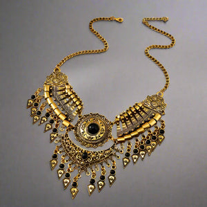 Decorative gold necklace with black accents on a wooden surface