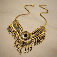 Decorative gold necklace with black accents on a wooden surface