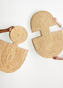 Two woven placemats held by hands on a white background