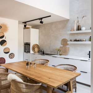 Modern kitchen with wooden dining table, wicker chairs and woven african wall art