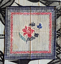 Decorative fabric dinner napkin with floral design and intricate border on a textured background