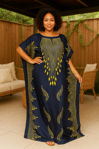 Woman wearing a navy blue kaftan dress with yellow patterns in an outdoor setting