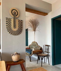Decorative wall art piece on a wall with a chair and table in the foreground.