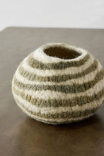 Striped felted vase on a reflective surface with a neutral background