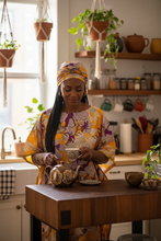 Woman in a kitchen setting, holding a teacup and teapot.
