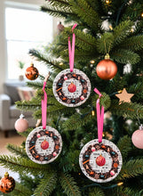 Decorative pink Christmas ornaments hanging on a tree with pink ribbons.