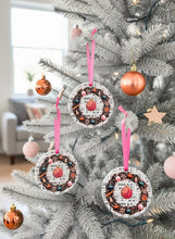 Decorative Christmas pink ornaments hanging on a tree with pink ribbons.