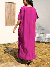 Woman wearing a bright pink dress standing on a paved patio.