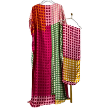Colorful polka dot dress on a hanger against a white background