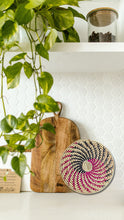 Wooden cutting board and woven basket on a white surface with greenery