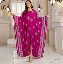 Woman wearing a vibrant pink dress with white patterns in an elegant indoor setting.